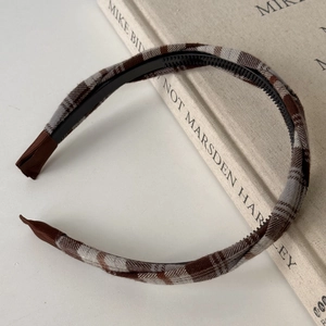 Detailed view of plaid fabric headband with non-slip inner teeth on a linen book
