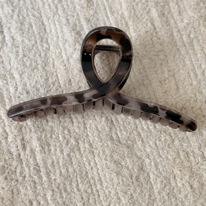 Detail view of a large leopard print hair claw clip on beige knitted fabric background