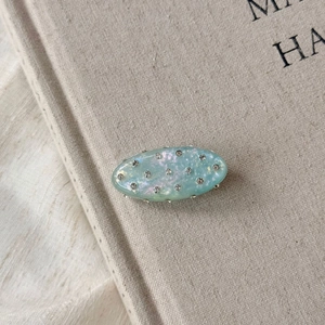 Gros plan détaillé d'une pince à cheveux ovale vert menthe avec strass brillants