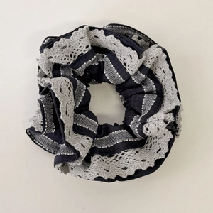 Dettaglio di un elastico nero con bordo in pizzo a contrasto e trama plissettata retrò
