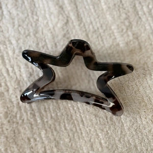 Detail view of star-shaped leopard print hair claw clip on soft knitted fabric background