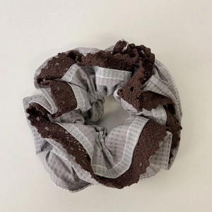 Dettaglio dell'elastico per capelli a quadretti grigi con bordo in pizzo marrone