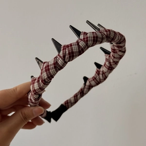 Dettaglio di un cerchietto a scacchi bianchi e rossi con borchie nere stile punk