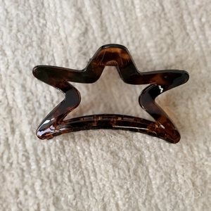 Star-shaped hair claw clip with dark leopard print texture and metal spring mechanism