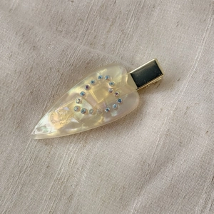Detail of acetate heart hair clip with blue rhinestones and gold metal duckbill clamp