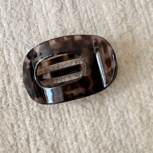 Detail of leopard print hair claw clip made of polished resin on a beige fabric background