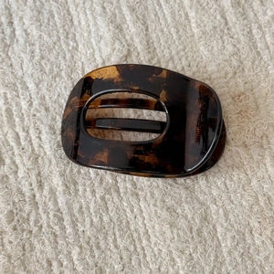 Detail view of tortoiseshell hair claw clip with amber pattern on knit background
