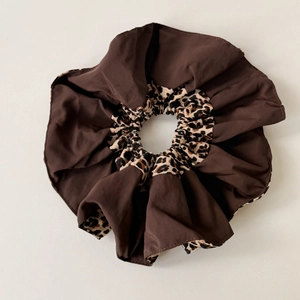 Detail of oversized scrunchie featuring brown solid fabric and leopard print textures