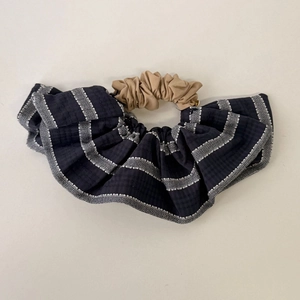 Dettaglio delle trame di tessuto a righe blu e kaki su un elastico per capelli