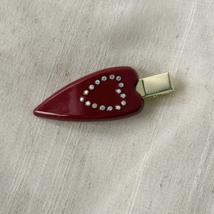 Close-up of deep red heart hair clip with sparkling rhinestones and golden metal base
