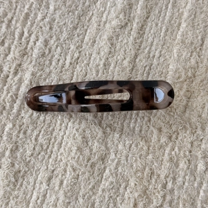 Macro detail of tortoiseshell leopard hair claw clip on beige textured fabric