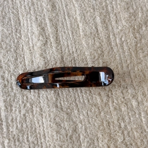 Detail of tortoise shell hair clip with glossy acetate texture on knit background