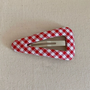 Macro detail of red gingham fabric wrapped snap hair clip with a classic triangle design