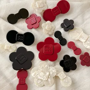 Macro detail of acetate flower and bow hair clips with refined embossed logo texture