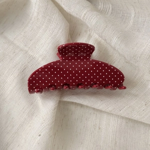 Macro shot of dark red acetate shark clip with white polka dots and star rhinestones