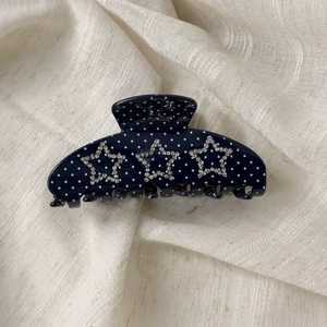 Close-up of blue polka dot hair claw clip with sparkling rhinestone star details