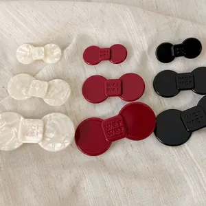 Detailed close-up of acetate bow hair clips in cream, burgundy, and black finishes
