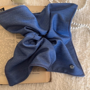 Blue denim scrunchie headscarf with metal tag on a vintage book and pearl background