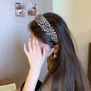 Woman wearing a vintage leopard print headband and gold hoop earrings in a cozy room