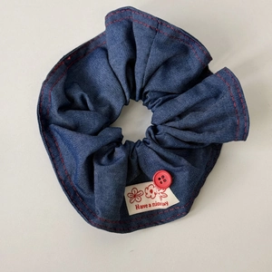 Detail of navy denim headband with red contrast stitching, red button, and flower tag