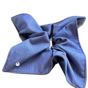 Denim fabric scrunchie in blue with red stitching and a silver brand charm detail