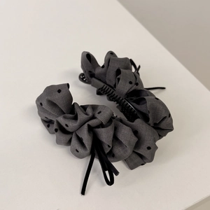 Detailed view of dark grey polka dot banana hair clip with elegant black velvet bow