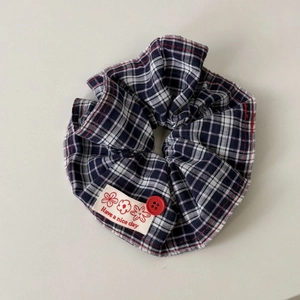 Detail of navy blue plaid hair tie with red button and Have a nice day label decoration