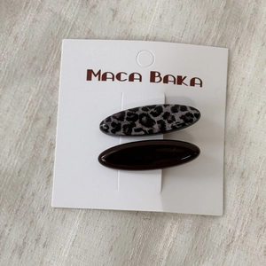 Detail of two resin hair clips in leopard print and solid brown on display card