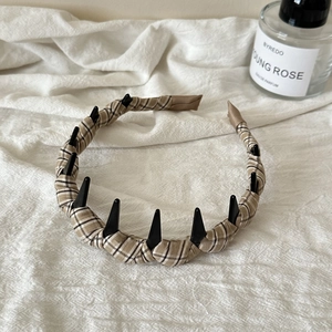 Dettaglio del cerchietto in tessuto scozzese con punte punk nere e denti antiscivolo