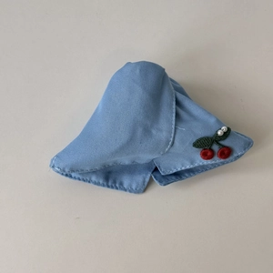 Detail of light blue denim hair claw with embroidered red cherries and pearl accents