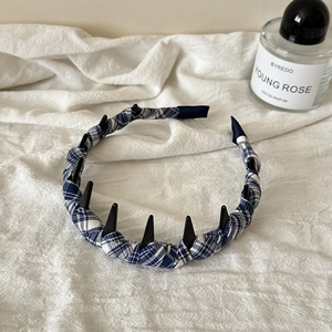 Dettaglio del cerchietto in tessuto scozzese blu con borchie a cono nere e denti antiscivolo