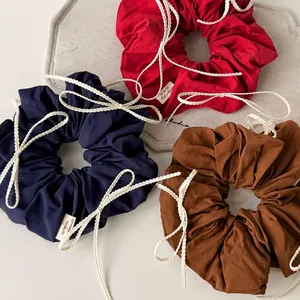Trio of cotton bow scrunchies in red, navy, and brown with lace edge details