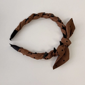 Detailed view of brown polka dot bow headband with non-slip inner plastic teeth