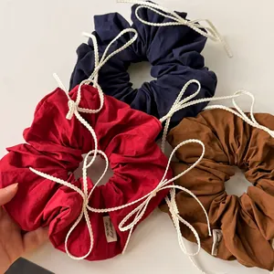 Three cotton bow scrunchies in red, navy, and brown with decorative white lace wavy ribbons