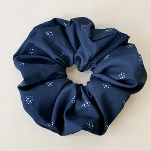 Dettaglio dello scrunchie floreale blu scuro con motivi a stella e trama pieghettata