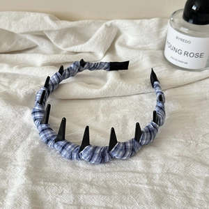 Dettaglio del cerchietto in tessuto scozzese blu con punte nere su lino bianco