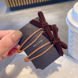 Detail van twee bruine fluwelen strik haarclips op displaykaart in een café-setting