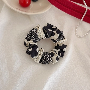 Close-up of a stylish black and white polka dot fabric scrunchie with pleated texture