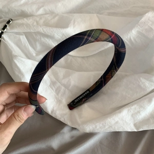 Detail of British plaid headband showing handmade label on blue tartan fabric