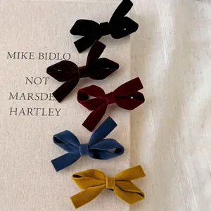 Vintage velvet bow hair clips in black, burgundy, blue, and yellow on book background