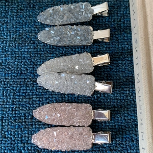 Detail of glitter hair clips in silver, white and pink on a blue textured surface