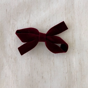 Detail of burgundy velvet bow hair clip showing luxury soft fabric texture and classic style