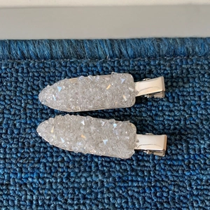 Detail of silver hair clips with sparkling crystal stones on blue woven texture fabric