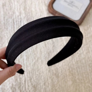 Close-up of black padded headband showing textured fabric detail and thick sponge padding