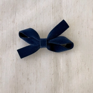 Detail showing the rich texture of the deep blue velvet bow hair clip with soft lighting
