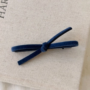 Detailed view of a dark blue velvet bow hair clip with a metallic duckbill grip