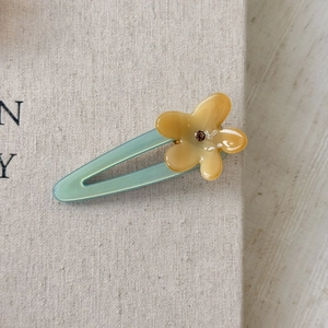 Macro shot of yellow flower acetate hair clip with turquoise base and rhinestone center