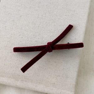 Detailed macro view of dark red velvet bow hair clip with secure black metal duckbill grip