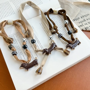 Vintage dachshund silk scarf necklace set in warm brown tones on an antique book
