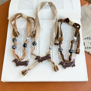Vintage dachshund silk scarf necklace set with tortoiseshell beads on open book background